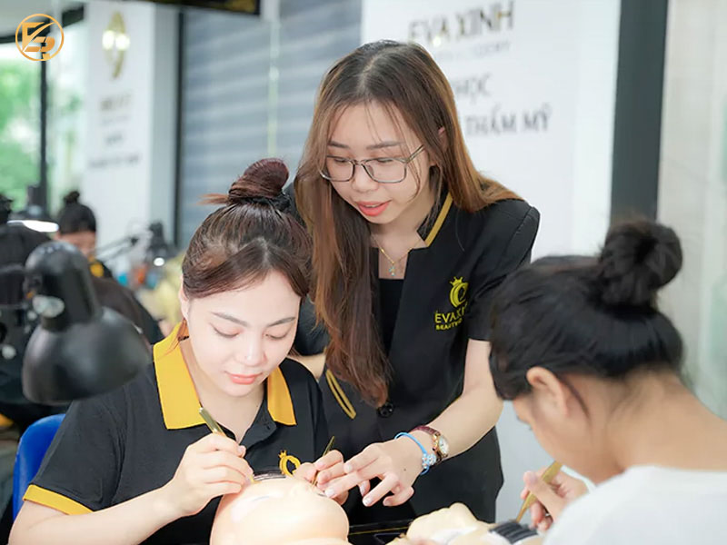 Giảng viên đang hỗ trợ học viên thực hành nối mi và thẩm mỹ tại Eva Xinh, địa chỉ học điêu khắc chân mày và thẩm mỹ uy tín.