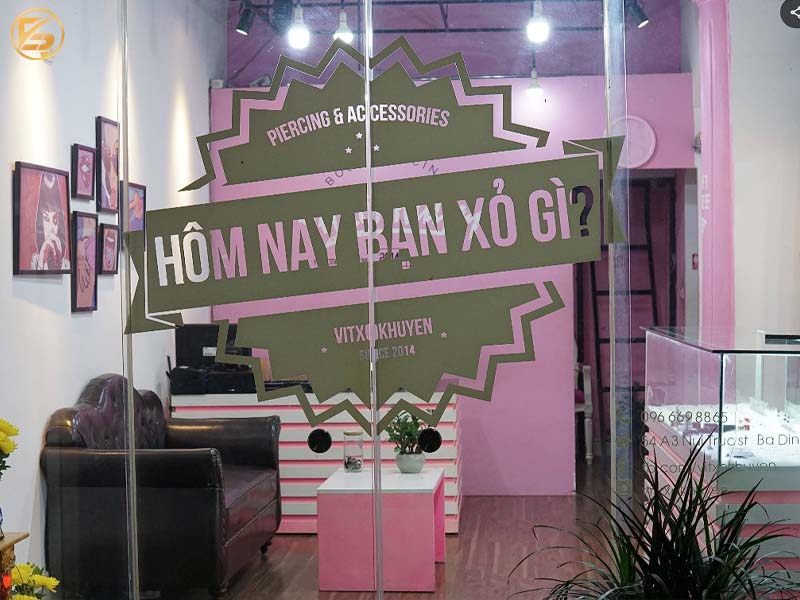 Cửa kính tiệm xỏ khuyên Vít Xỏ Khuyên với slogan Hôm nay bạn xỏ gì và không gian cửa hàng tông màu hồng quyến rũ