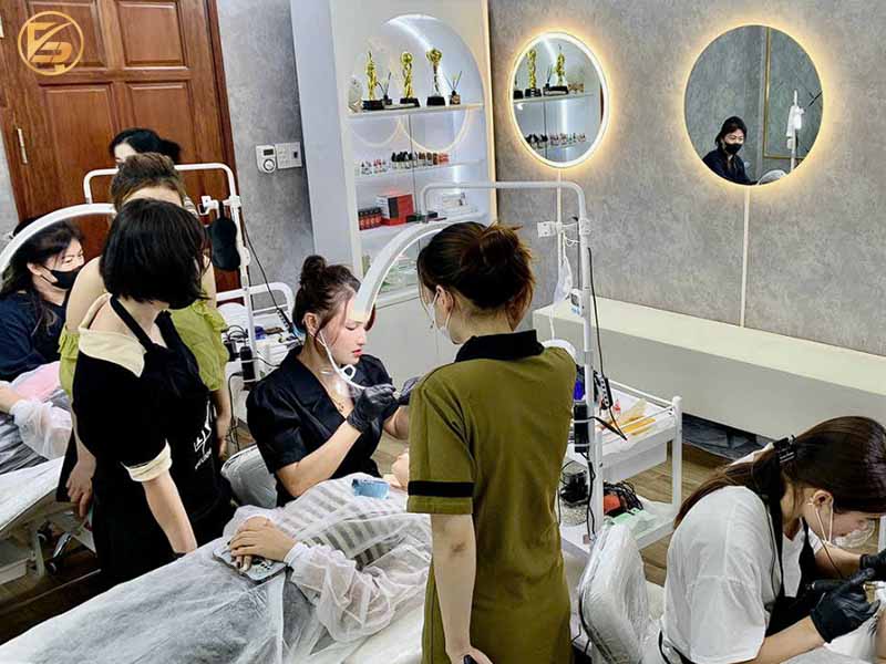 Không gian lớp học thực hành phun xăm thẩm mỹ chuyên nghiệp với giảng viên cầm tay chỉ việc cho từng học viên.